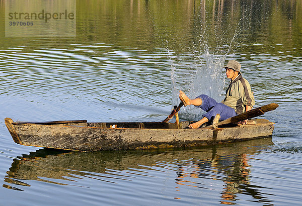 Fischer auf einem Holzboot fischt mit traditioneller Stockschlag-Methode  Tuyen Lam See  Dalat  Zentrales Hochland  Vietnam  Asien