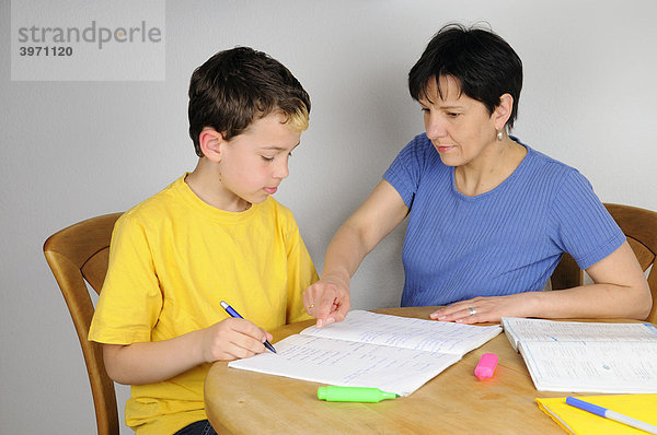 Junge macht Hausaufgaben für die Schule  Mutter unterstützt ihn dabei
