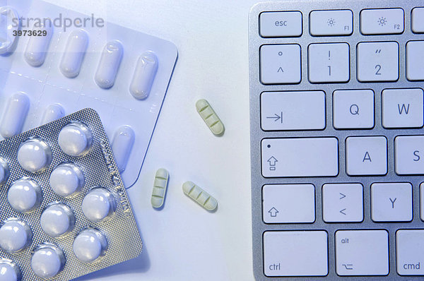 Aufputschtabletten und Psychopharmaka neben Computertastatur  Symbolfoto Doping am Arbeitsplatz