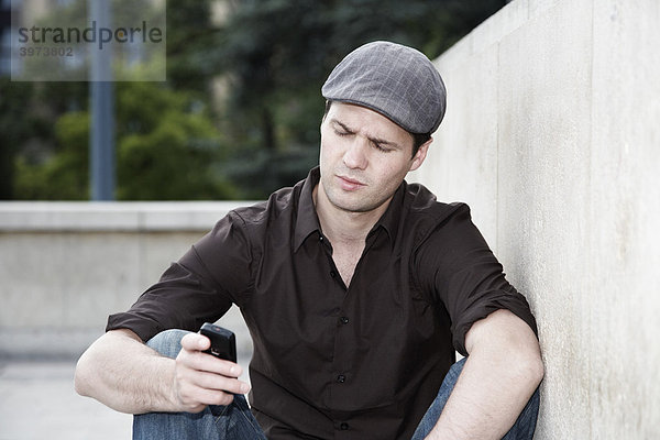 Junger Mann liest auf seinem Handy eine SMS