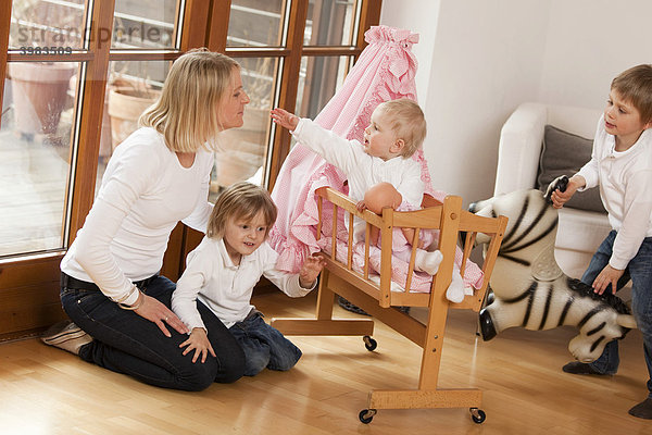 Mutter mit drei Kindern  1  3 und 6 Jahre  spielen mit Puppenwagen