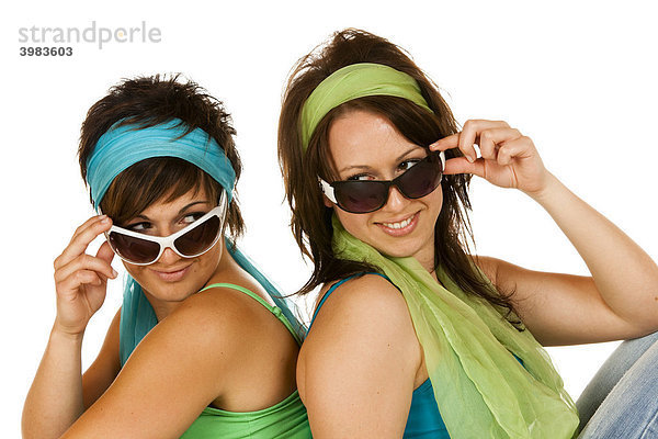 Zwei junge Frauen mit Sonnenbrillen sitzen Rücken an Rücken