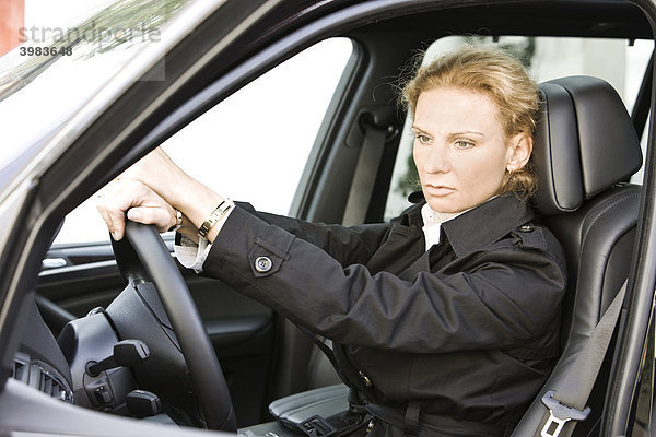 Frau am Steuer eines Luxus-Geländewagens  nachdenklich