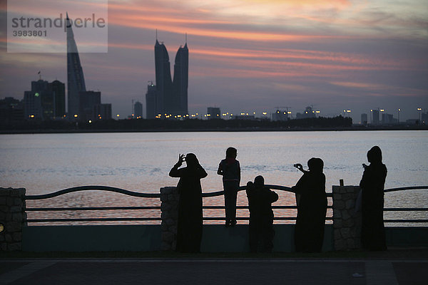 Skyline von der Corniche am King Faisal Highway gesehen  Muharraq Seite  World Trade Center Gebäude  links  daneben die Türme des Financial Harbour Komplex  abendliche Spaziergänger an der Corniche  Hauptstadt Manama  Königreich Bahrain  Persischer Golf