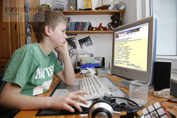 Junge  13 Jahre alt  surft mit seinem Computer zuhause im Internet auf einer Lernseite für Schüler Englisch Lektionen online