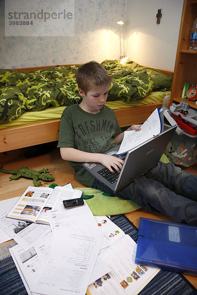 Junge  11 Jahre alt  arbeitet mit seinem Computer zuhause in seinem Kinderzimmer  macht Hausaufgaben für die Schule