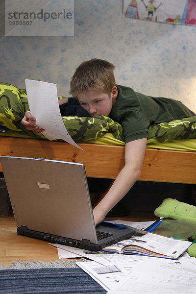 Junge  11 Jahre alt  arbeitet mit seinem Computer zuhause in seinem Kinderzimmer  macht Hausaufgaben für die Schule