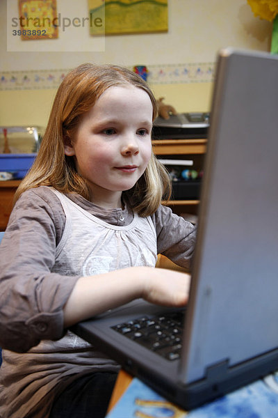 Mädchen  7 Jahre  arbeitet mit einem Computer zuhause im Kinderzimmer  macht Hausaufgaben für die Schule  Lernsoftware