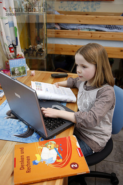 Mädchen  7 Jahre  arbeitet mit einem Computer zuhause im Kinderzimmer  macht Hausaufgaben für die Schule  Lernsoftware