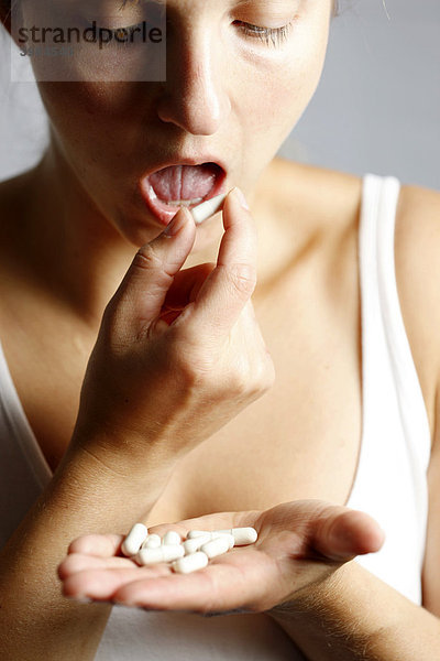 Junge Frau nimmt Tabletten  Kapseln  ein