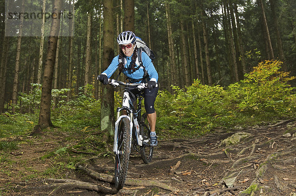 Mountainbike-Fahrerin auf Wurzeltrail im Wald am Heuberg bei Nußdorf am Inn  Bayern  Deutschland
