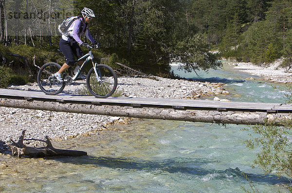 Mountainbike-Fahrerin auf schmaler Holz-Brücke über die Isar südöstlich von Scharnitz  Tirol  Österreich