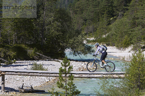 Mountainbike-Fahrerin auf kleiner Holz-Brücke über die Isar südöstlich von Scharnitz  Tirol  Österreich