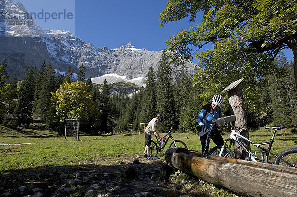 Mountainbiker und Mountainbikerin machen Rast an einem Brunnen  sie füllt Fahrradflasche auf  Kleiner Ahornboden  Hinterriß  Tirol  Österreich