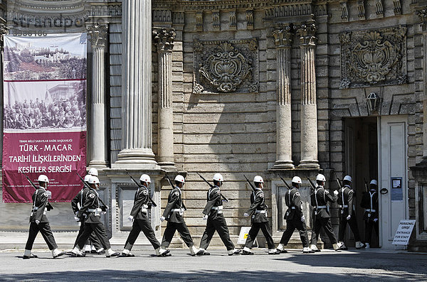 Gruppe von Wachsoldaten mit weißem Helm marschiert vor dem Dolmabahce-Palast  Sultanspalast aus dem 19. Jh.  Besiktas  Istanbul  Türkei
