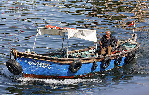 Mann steuert pittoreskes Holzboot für Personentransport über das Goldene Horn  Istanbul  Türkei
