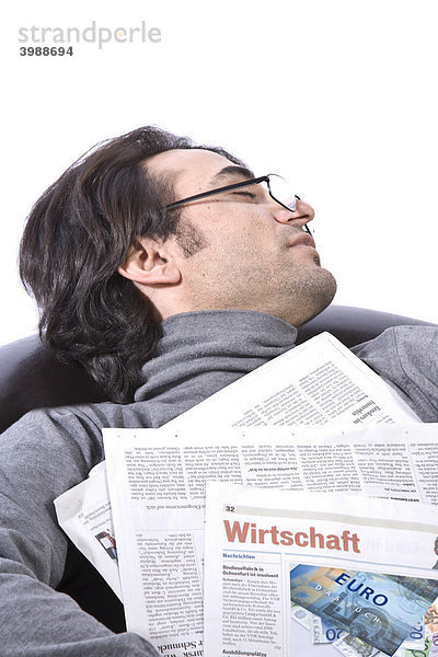 Junger  schlafender Mann im Ledersessel mit Zeitung