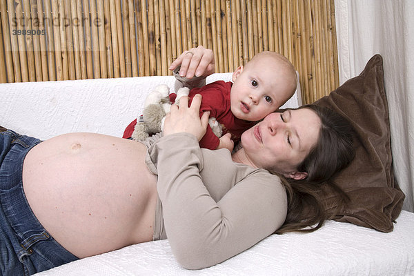 Schwangere Frau spielt mit Kleinkind auf Sofa
