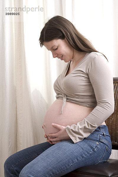 Schwangere Frau betrachtet ihren Bauch