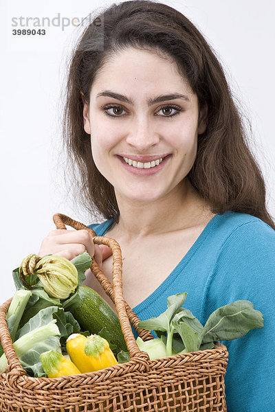 Mädchen mit Gemüsekorb strahlt zum Betrachter