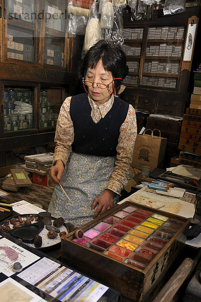 Verkäuferin demonstriert kniend auf einer Tatamimatte verschiedene Mineralfarben für Nihonga-Malerei in einem traditionellen Geschäft für Künstlerbedarf  Kyoto  Japan  Asien