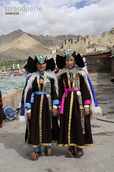 Ladakhi in traditioneller Kleidung mit Perak  Kopfbedeckung mit Türkisen  im Hintergrund der Palast  Leh  Ladakh  Himalaja  Nordindien  Indien