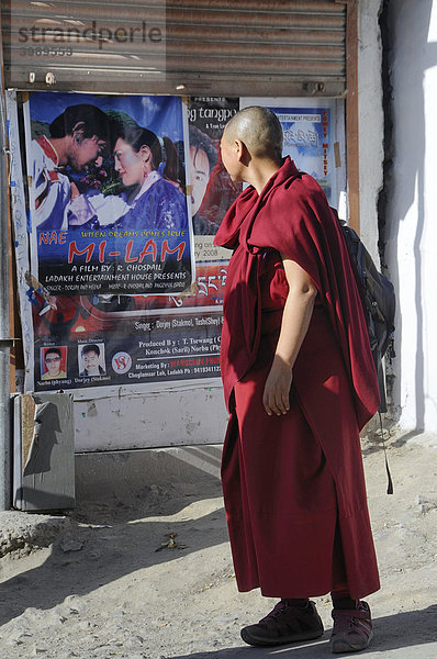 Buddhistischer Mönch betrachtet eine moderne Kinoreklame in Leh  Ladakh  Nordindien  Indien  Himalaja