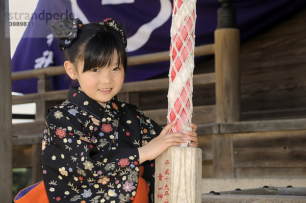 Mädchen im Kimono läutet die Glocke am shintoistischen Schrein während des Kirschblütenfestes in Sasayama  Japan  Asien