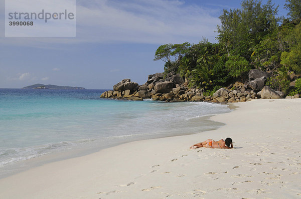 Frau liegt auf Sandstrand mit Granitfelsen und tropischer Vegetation  Anse Georgette  Insel Praslin  Seychellen  Afrika  Indischer Ozean