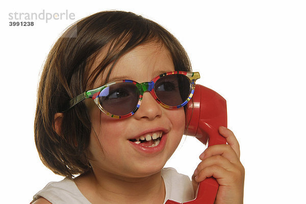 Vierjähriges Mädchen mit Telefonhörer und Sonnenbrille