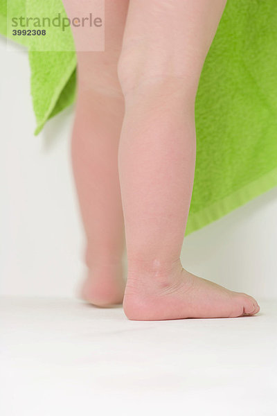 Beine eines Kleinkindes vor einem grünen Handtuch