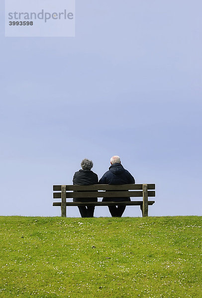 Senioren-Paar auf einer Bank auf einem Deich