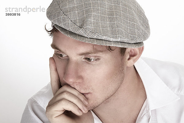 Portrait eines jungen  nachdenklichen Mannes im weißen Hemd und Mütze