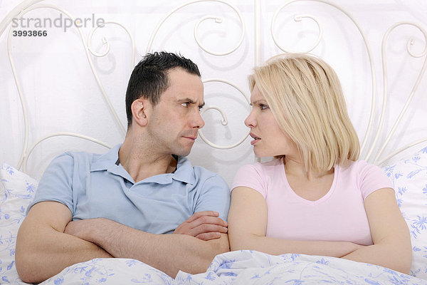 Paar im Bett hat Streit  Mann und Frau mit verschränkten Armen blicken sich an