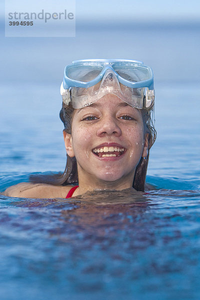 Mädchen mit Taucherbrille im Schwimmbad  lacht in die Kamera