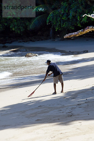 Kreole macht den Strand sauber  Insel Mahe  Seychellen  Indischer Ozean  Afrika