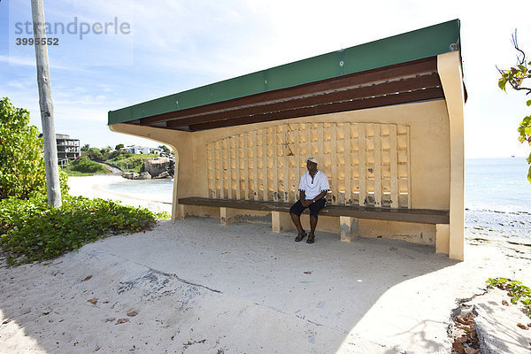 Ein Mann wartet in einer Bushaltestelle auf den öffentlichen Bus  Glacis  Insel Mahe  Seychellen  Indischer Ozean  Afrika