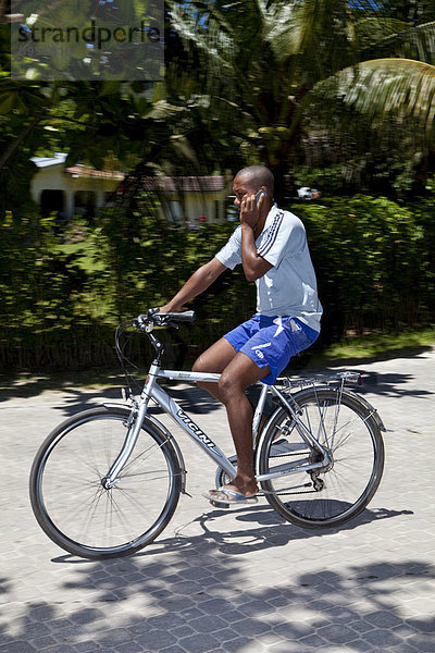 Einheimischer Fahrradfahrer mit Handy  Insel La Digue  Seychellen  Indischer Ozean  Afrika