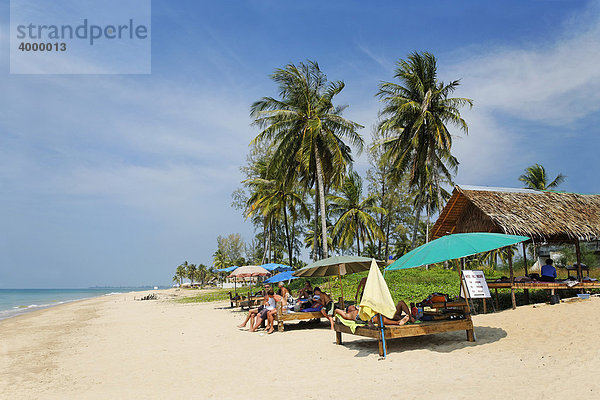 Menschen am Strand mit Sonnenschirmen vor Palmen und Schilfdach  Andamanisches Meer  Khao Lak  Phuket  Thailand  Asien