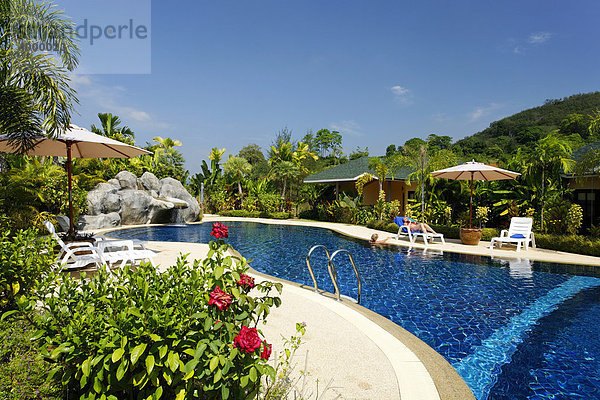 Frau auf Sonnenliege am Pool mit Bungalows in Grünanlage  Palm Garden Resort  Khao Lak  Phuket  Thailand  Asien