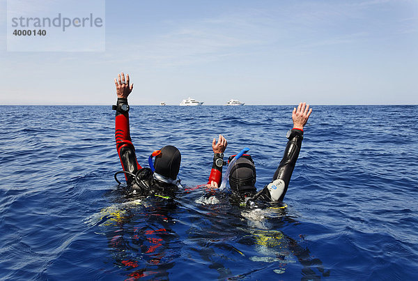 Abgetriebene Taucher auf dem Meer versuchen durch Winken Aufmerksamkeit von Personen auf Tauchschiffen am Horizont zu erregen  Ägypten  Rotes Meer  Afrika
