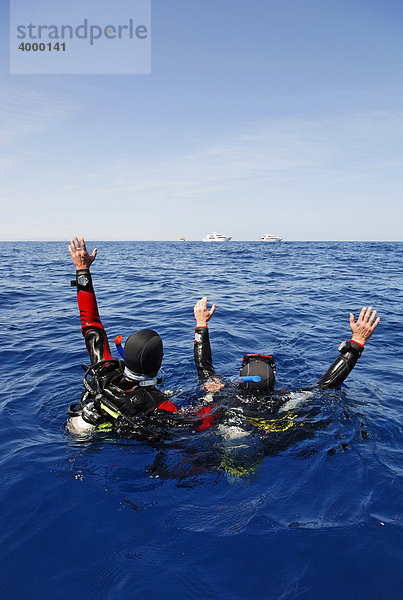 Abgetriebene Taucher auf dem Meer versuchen durch Winken Aufmerksamkeit von Personen auf Tauchschiffen am Horizont zu erregen  Ägypten  Rotes Meer  Afrika
