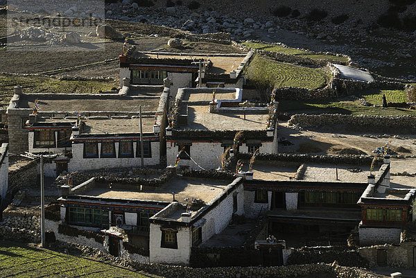 Tibetische Bauernhäuser mit tibetischer Bemalung und Yakdung Brennmaterial zum Abtrocknen auf dem gestampften Lehmflachdach vor Felderwirtschaft mit traditoneller Bewässerungstechnik bei Nyalam  Tibet  China  Asien