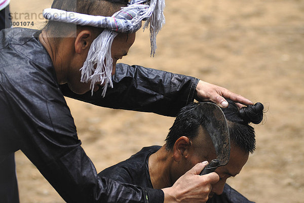 Traditionelle Haarrasur der Basha mit einer Sichel bei einem Mann mit Haarknoten der Basha-Minderheit  kleinste Minderheit in China  Basha  Guizhou  China  Asien