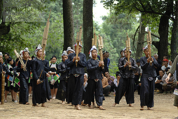 Männer und Frauen eines Lusheng Orchesters in Tracht der Basha Minderheit aus geklopfter schwarzer Baumwolle mit Bambusflöten und Mundorgeln der Basha Minderheit  Basha  Guizhou  China  Asien