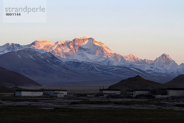 Dämmerung  Sonnenuntergang vor verschneitem Gebirgszug des Cho Oyo  8112 m  in der Hochebene von Tingri mit tibetischen Gebäuden des Dorfes Old Tingri  Tibet  China  Asien