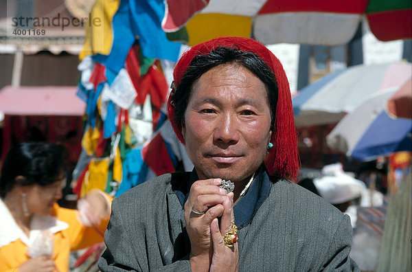 Tibetischer Mann mit rotem Haarknoten  vom Stamm der Kampha  hält Symbol des tibetischen Schneelöwen als Hosenknopf mit beiden Händen  in der tibetischen Nationalflagge enthaltenes Symbol  heute in Tibet verboten  Lhasa  Tibet  China  Asien