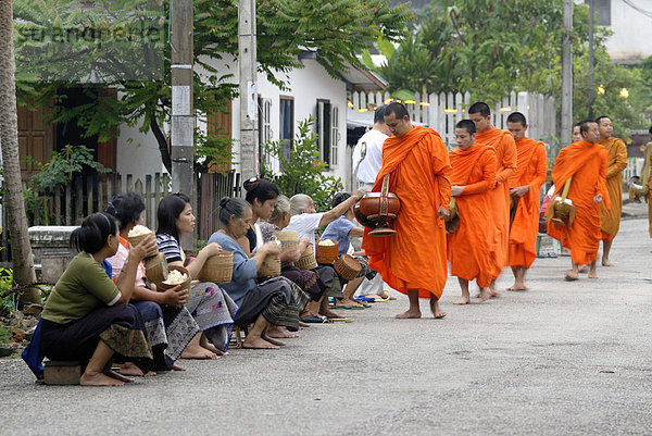Morgendlicher Almosengang  Bettelgang  Thakbat der Mönche und Novizen der Klosteranlagen in Luang Prabang  Männer und Frauen verteilen Lebensmittel an Mönche  Laos  Südostasien