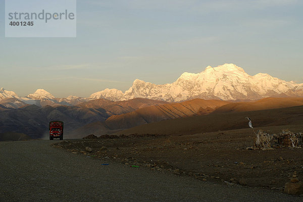 Verschneiter Himalayahauptkamm mit Shishapangma 'Platz der Heiligen'  8027 m Höhe  mit Bergstraße und orangem Truck  LKW  der Marke Dong Feng in der Morgensonne am Tarong-la-Pass  Tingri  Nyalam  Tibet  China  Asien