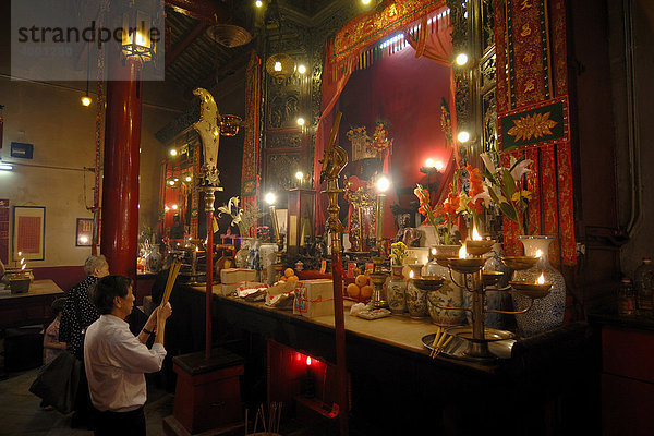 Mann und Frau beten mit Räucherstäbchen  Rauchopfer  vor einem chinesischen buddhistischen Altar mit brennenden Kerzen und Opfergaben im Man Mo Tempel  Hongkong  China  Asien